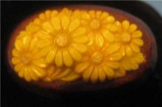 For sale is a lovely, deeply carved, daisies in plastic on wood brooch 